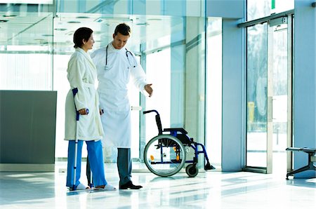 Male doctor assisting a female patient in walking on crutches Stock Photo - Premium Royalty-Free, Code: 6108-05860443