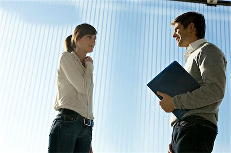 pictures of a person with a belt on - Side profile of a businessman holding a laptop and talking to a businesswoman Stock Photo - Premium Royalty-Free, Code: 6108-05860464