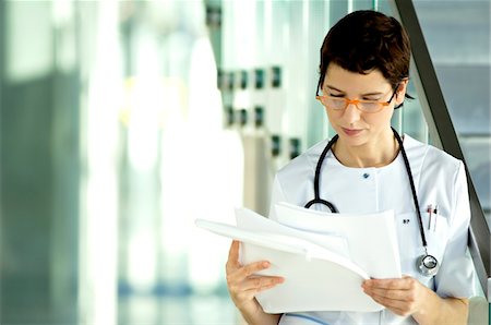 simsearch:6108-05860439,k - Female doctor reading medical records Stock Photo - Premium Royalty-Free, Code: 6108-05860400
