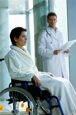 simsearch:6108-05860439,k - Female patient sitting in a wheelchair and a male doctor standing in the background Stock Photo - Premium Royalty-Free, Code: 6108-05860427
