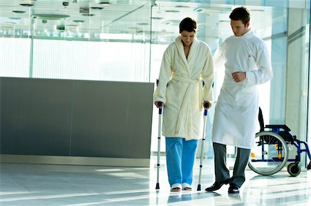 patient walking hospital halls - Male doctor assisting a female patient in walking on crutches Foto de stock - Sin royalties Premium, Código: 6108-05860430