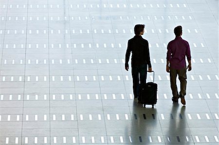 simsearch:6108-05860566,k - Rear view of two men walking at an airport lobby Stock Photo - Premium Royalty-Free, Code: 6108-05860546