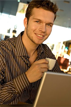 Portrait of a businessman holding a tea cup in front of a laptop Stock Photo - Premium Royalty-Free, Code: 6108-05860519