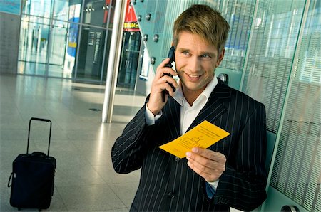 passenger with phone - Businessman holding an airplane ticket and talking on a mobile phone at an airport Stock Photo - Premium Royalty-Free, Code: 6108-05860537