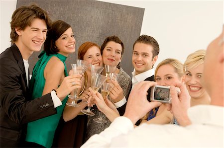 Mature man taking a picture of a group of people toasting with wine glasses in a party Stock Photo - Premium Royalty-Free, Code: 6108-05860640