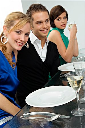 simsearch:6108-05874120,k - Jeune homme avec deux jeunes femmes lors d'une réception Photographie de stock - Premium Libres de Droits, Code: 6108-05860657