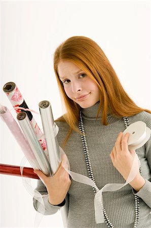 Portrait of a young woman holding rolls of wrapping papers Stock Photo - Premium Royalty-Free, Code: 6108-05860631