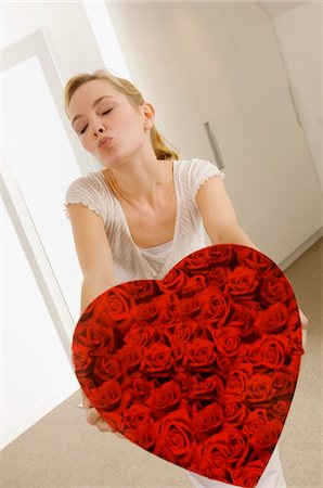 face with rose - Young woman holding a heart shape gift and puckering her lips Stock Photo - Premium Royalty-Free, Code: 6108-05860815