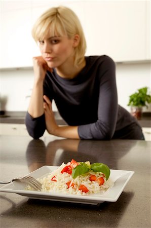 simsearch:6108-05862966,k - Plate of rice in front of a young woman leaning against a kitchen counter Stock Photo - Premium Royalty-Free, Code: 6108-05860825