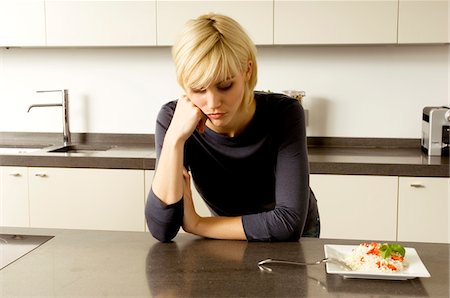 simsearch:6108-05862966,k - Young woman leaning against a kitchen counter and thinking Stock Photo - Premium Royalty-Free, Code: 6108-05860837