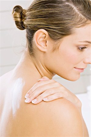 shoulder (anatomy) - Side profile of a young woman applying moisturizer on her shoulder Foto de stock - Sin royalties Premium, Código: 6108-05860941