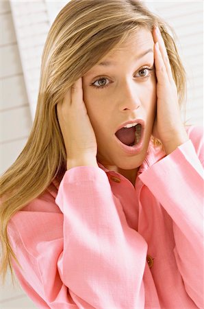 Close-up of a young woman shouting in shock Stock Photo - Premium Royalty-Free, Code: 6108-05860944