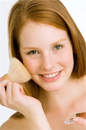 Portrait of a young woman applying blush on her cheek Stock Photo - Premium Royalty-Free, Code: 6108-05860978