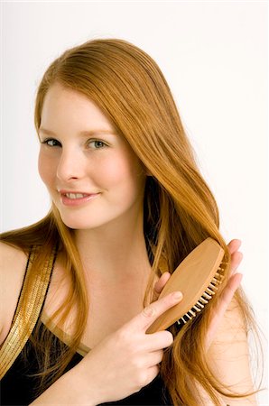 soin capillaire - Portrait d'une jeune femme se brosser ses cheveux et souriant Photographie de stock - Premium Libres de Droits, Code: 6108-05860999