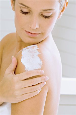 selfish - Side profile of a young woman applying moisturizer on her shoulder Stock Photo - Premium Royalty-Free, Code: 6108-05860930