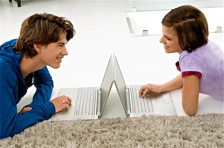 simsearch:6108-05861211,k - Side profile of a young woman and a teenage boy looking at each other and using laptops Foto de stock - Sin royalties Premium, Código: 6108-05861047