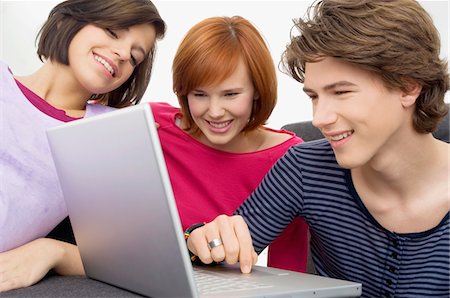 Close-up of two young women and a teenage boy looking at a laptop Stock Photo - Premium Royalty-Free, Code: 6108-05861057