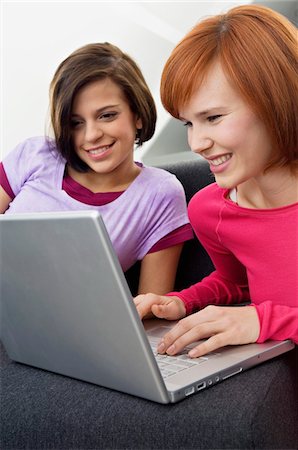 Two young women using a laptop and smiling Stock Photo - Premium Royalty-Free, Code: 6108-05861063