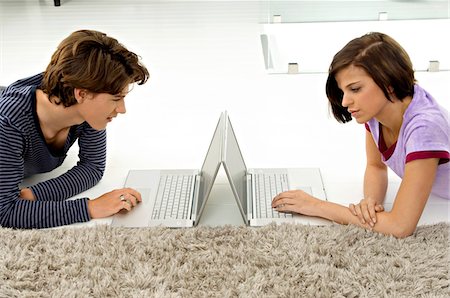 Side profile of a teenage boy and a young woman using laptops Stock Photo - Premium Royalty-Free, Code: 6108-05861077