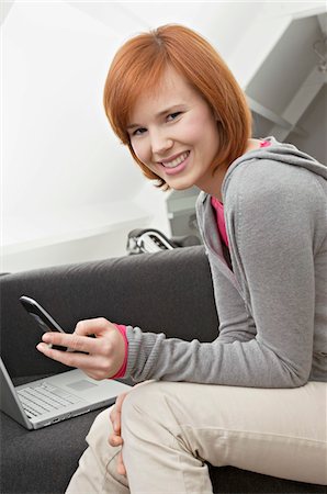 simsearch:6108-05861100,k - Portrait of a young woman using a mobile phone and smiling Fotografie stock - Premium Royalty-Free, Codice: 6108-05861082