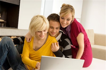 simsearch:6108-05861100,k - Young man with two young women looking at a laptop and smiling Fotografie stock - Premium Royalty-Free, Codice: 6108-05861093