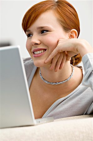 simsearch:6108-05860505,k - Close-up of a young woman sitting in front of a laptop and smiling Stock Photo - Premium Royalty-Free, Code: 6108-05861091