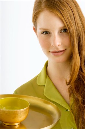 Portrait of a young woman holding a bowl of massage oil on a plate Stock Photo - Premium Royalty-Free, Code: 6108-05861017