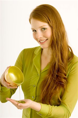 Portrait of a young woman pouring massage oil on her palm Stock Photo - Premium Royalty-Free, Code: 6108-05861021