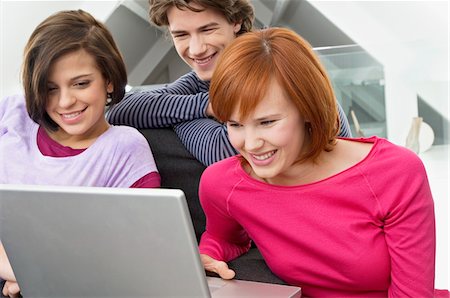 Close-up of two young women and a teenage boy looking at a laptop Stock Photo - Premium Royalty-Free, Code: 6108-05861027