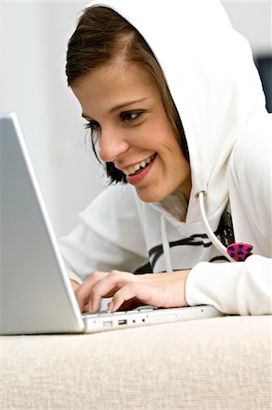 Side profile of a young woman using a laptop and smiling Stock Photo - Premium Royalty-Free, Code: 6108-05861031