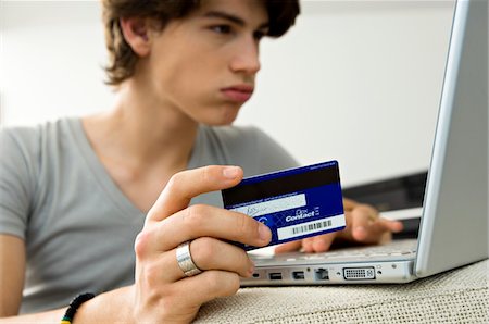 people holding cards in hand - Gros plan d'un adolescent à l'aide d'un ordinateur portable et maintenant une carte de crédit Photographie de stock - Premium Libres de Droits, Code: 6108-05861037