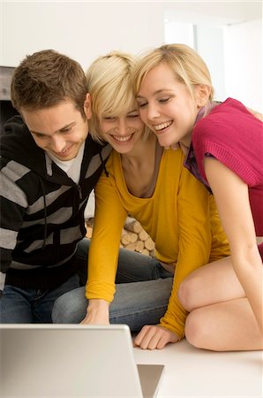 simsearch:6108-05860085,k - Young man with two young women looking at a laptop and smiling Foto de stock - Royalty Free Premium, Número: 6108-05861107