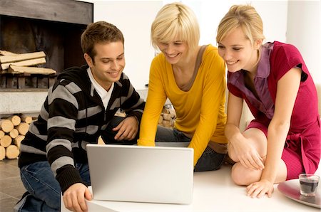 simsearch:6108-05861100,k - Young man with two young women looking at a laptop and smiling Fotografie stock - Premium Royalty-Free, Codice: 6108-05861135