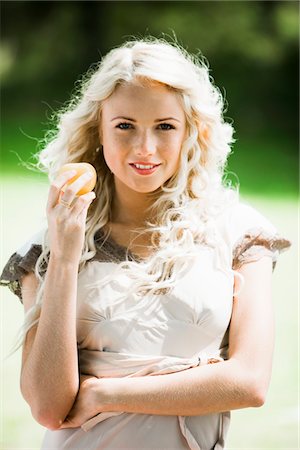 summer eating and clothes - Young woman holding a yellow tomato Stock Photo - Premium Royalty-Free, Code: 6108-05861398