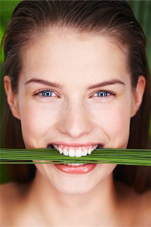 simsearch:6108-05857551,k - Young smiling woman holding plants between teeth Foto de stock - Sin royalties Premium, Código: 6108-05861325