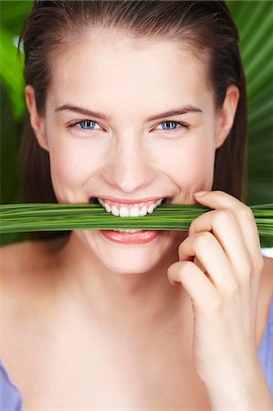 simsearch:6108-05857551,k - Young smiling woman holding plants between teeth Foto de stock - Sin royalties Premium, Código: 6108-05861337