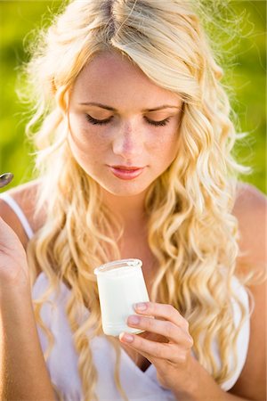 spoon in woman hand - Portrait of young woman eating a yoghurt Stock Photo - Premium Royalty-Free, Code: 6108-05861409