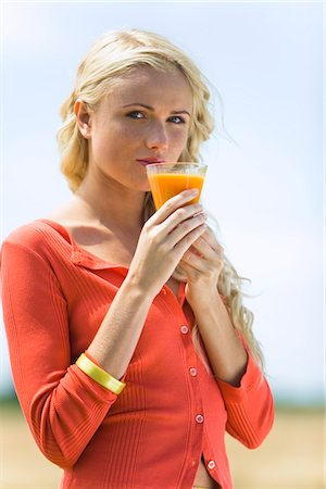 Portrait d'une jeune femme blonde tenant un verre de jus de fruits Photographie de stock - Premium Libres de Droits, Code: 6108-05861413