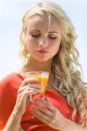 Portrait d'une jeune femme blonde tenant un verre de jus de fruits Photographie de stock - Premium Libres de Droits, Code: 6108-05861417