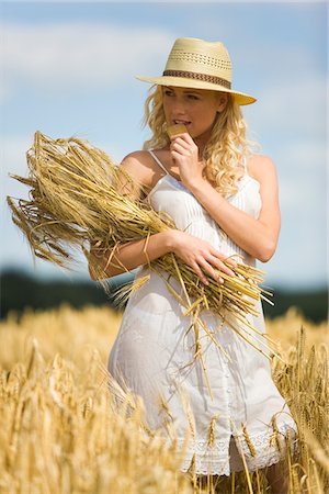 summer eating and clothes - Young woman in a wheat field Stock Photo - Premium Royalty-Free, Code: 6108-05861507