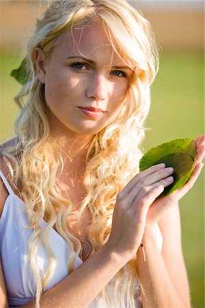 Young woman holding green leaves Stock Photo - Premium Royalty-Free, Code: 6108-05861524