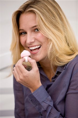 Woman eating a mushroom shaped candy Stock Photo - Premium Royalty-Free, Code: 6108-05861833