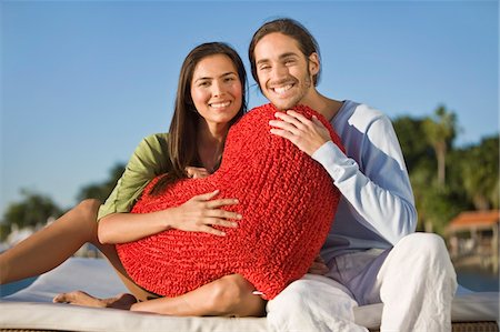 Portrait of a couple holding a heart shaped cushion Stock Photo - Premium Royalty-Free, Code: 6108-05862095