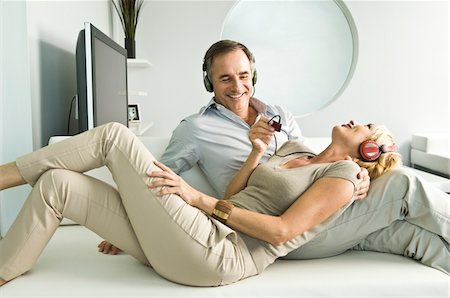 simsearch:6108-05862347,k - Couple à l'écoute de musique avec un casque et souriant Photographie de stock - Premium Libres de Droits, Code: 6108-05862347