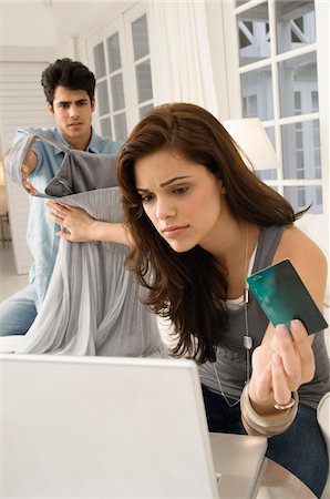 Woman shopping online with a credit card and her husband showing her a dress Stock Photo - Premium Royalty-Free, Code: 6108-05862329