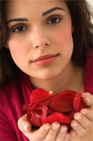 Portrait of a woman holding a handful of red rose petals Stock Photo - Premium Royalty-Free, Code: 6108-05862474