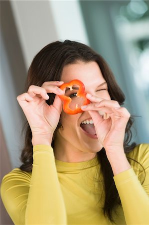 Woman looking through a slice of red bell pepper Stock Photo - Premium Royalty-Free, Code: 6108-05862403