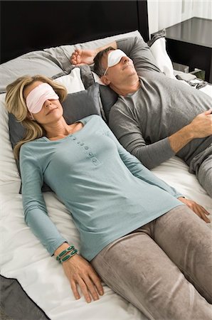 Couple sleeping in bed wearing eye masks Stock Photo - Premium Royalty-Free, Code: 6108-05862576