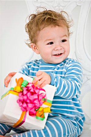 Baby boy holding a present in an armchair Stock Photo - Premium Royalty-Free, Code: 6108-05862704