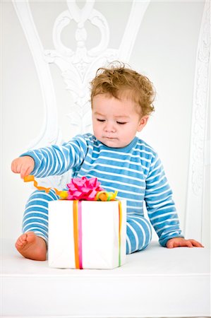 Baby boy playing with a present in an armchair Stock Photo - Premium Royalty-Free, Code: 6108-05862717